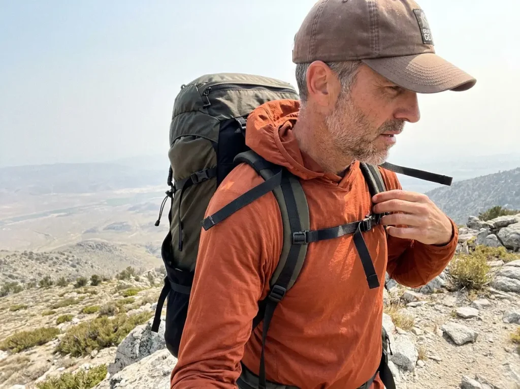 Hiker adjusting load-lifter straps to a 45-degree angle on a backpacking pack
