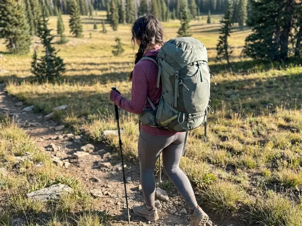 Woman test-walking a loaded women's-specific backpacking pack on a trail