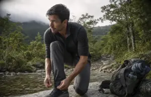 Best Waterproof Hiking Shoes Compared One Clear Winner Man lacing waterproof hiking shoes on a wet rock before crossing a shallow creek at first light