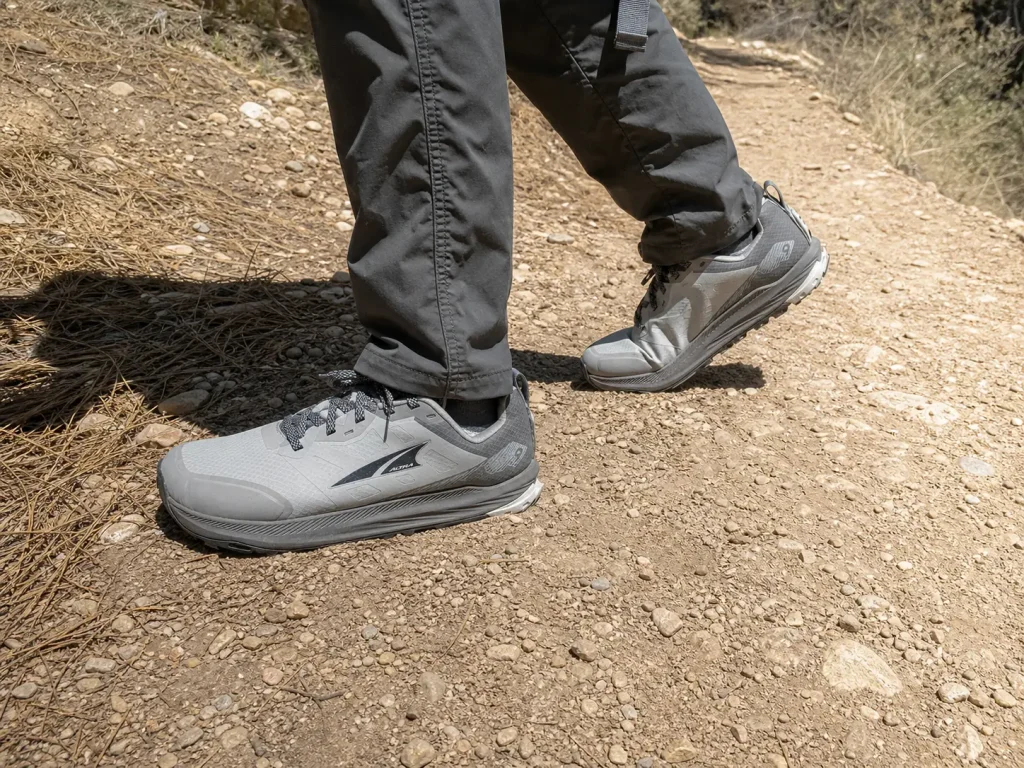 Hiker in lightweight hiking shoes pausing on dry singletrack to shake out a tired leg