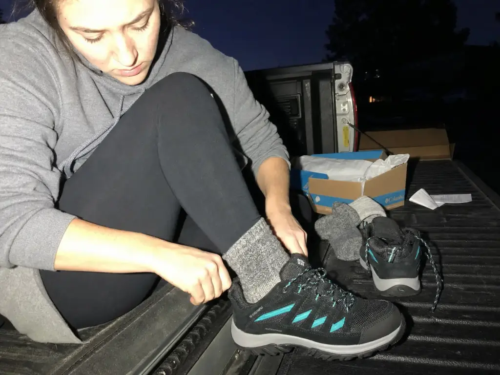 Woman trying on women's hiking shoes in the evening wearing real hiking socks, tailgate fitting check