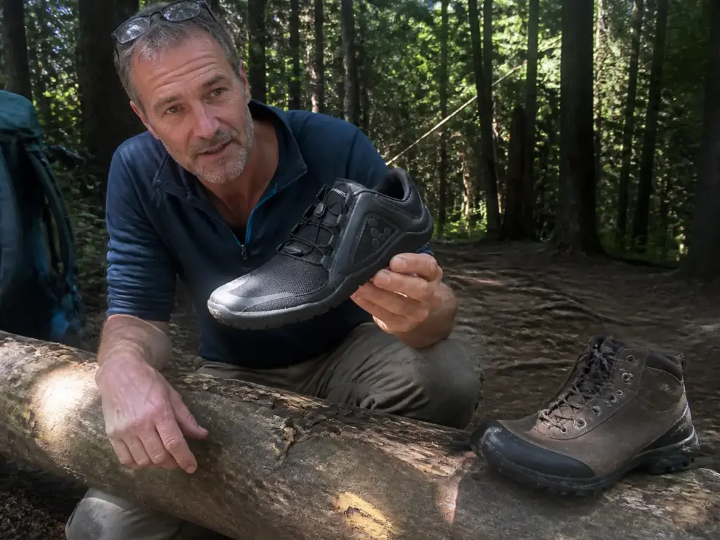 Trail running shoe next to a hiking shoe on a trail log, showing how differently the two are built