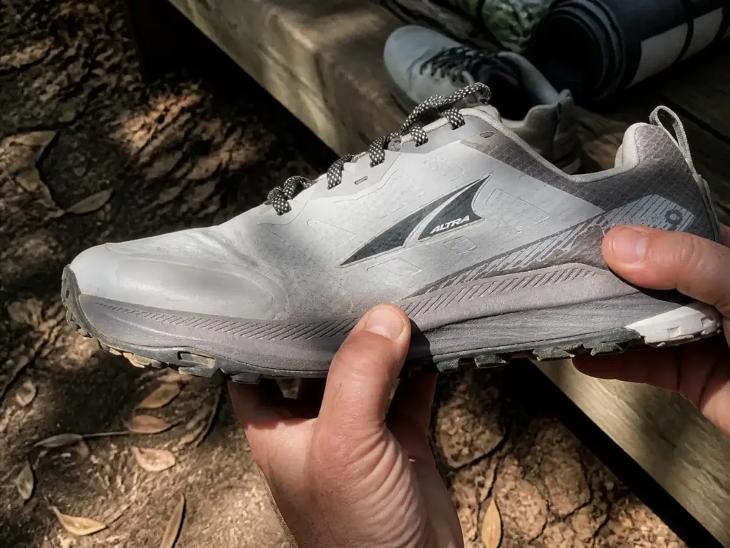 Worn Altra Lone Peak 9 trail runner held up showing compressed midsole after hundreds of trail miles