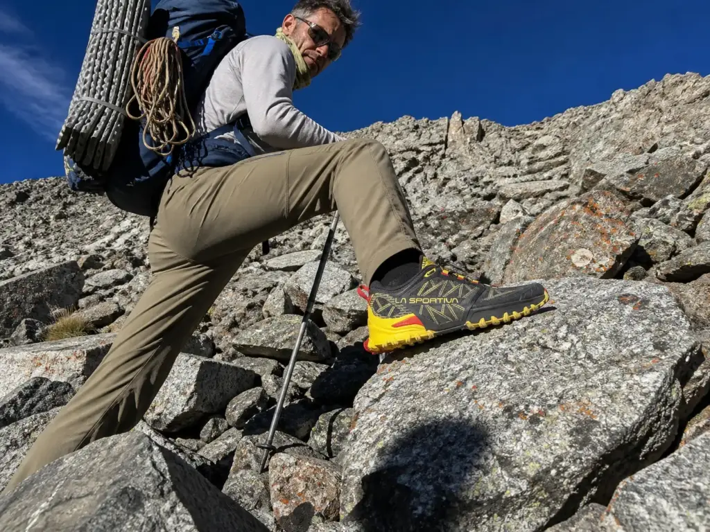 A backpacker on loose talus in technical trail runners with a heavy pack