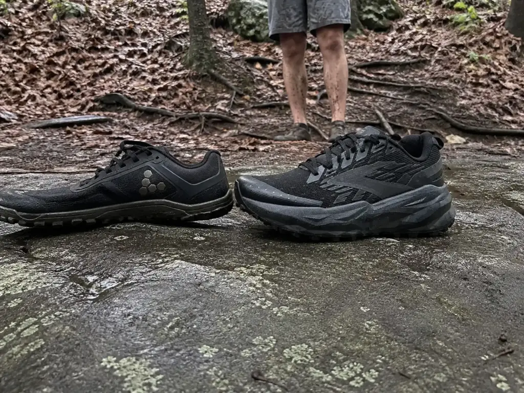 Two trail runners side by side on wet trail rock showing the difference in heel-to-toe drop