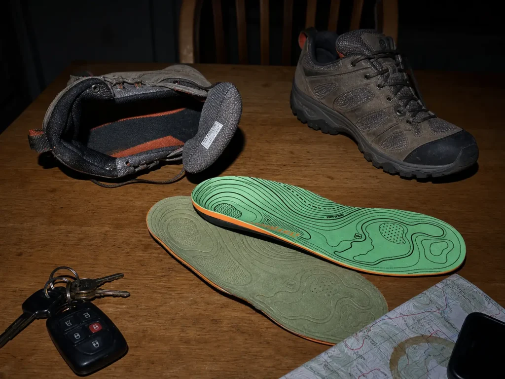 Superfeet Hike Support insole next to a flattened factory insole and an open hiking shoe