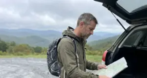 11 Best Hikes in North Carolina Blue Ridge Country Hiker checking a paper map at a Blue Ridge Parkway trailhead in North Carolina on an overcast fall morning