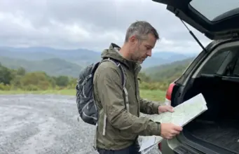 11 Best Hikes in North Carolina Blue Ridge Country Hiker checking a paper map at a Blue Ridge Parkway trailhead in North Carolina on an overcast fall morning