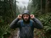 Rain Gear for Hiking Types Explained Plainly Hiker in rain gear adjusting a shell hood on a wet Cascades trail in steady rain