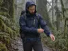 How to Stay Dry Hiking in the Rain Without Sweating Hiker in a rain jacket pausing on a wet forest trail while hiking in the rain