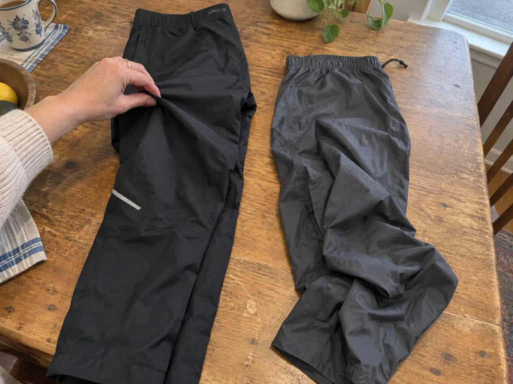 Two pairs of hiking rain pants laid out to compare fabric weight and construction