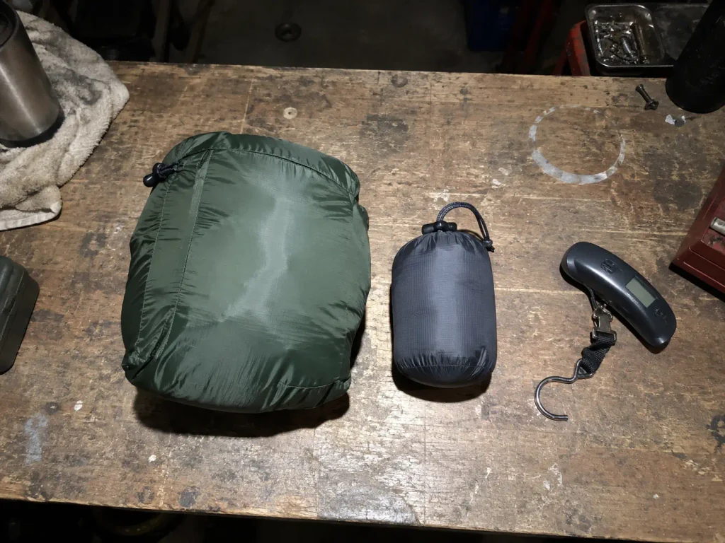Rain jacket and packed poncho side by side on a workbench before a hiking trip