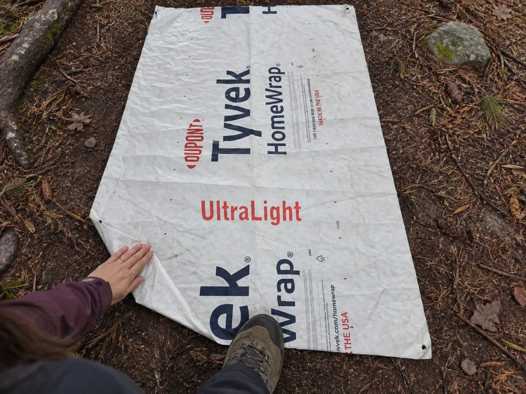 A Tyvek ground sheet laid out on forest dirt before pitching a 2 person backpacking tent