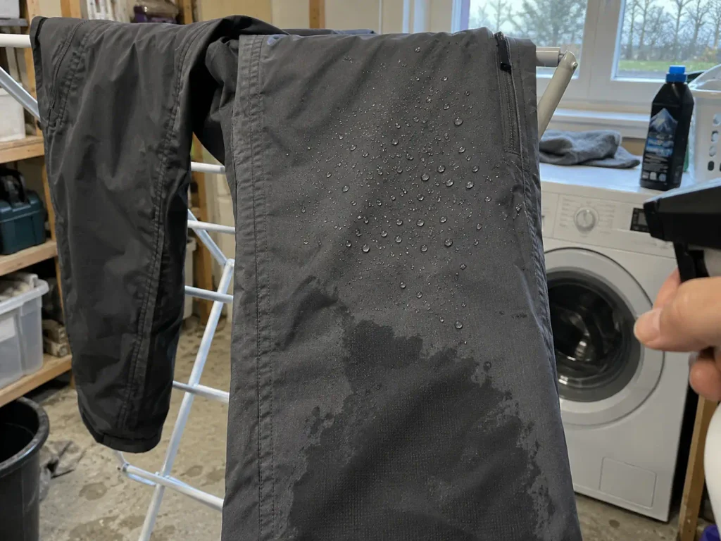 Rain pants hanging on a drying rack indoors after washing and reproofing