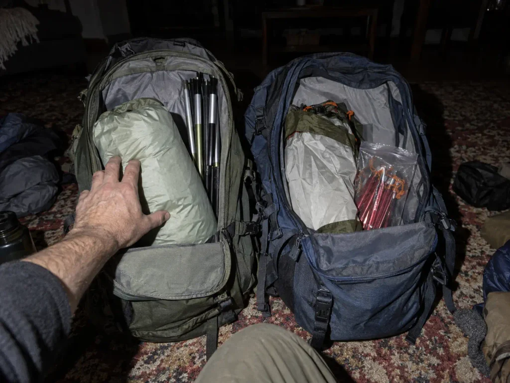 Tent poles body and rainfly divided between two backpacks the night before a trip
