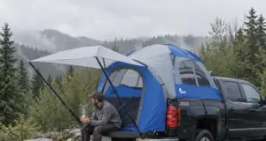 Truck Bed Tent Buying Guide Measure Your Bed First Man sitting on a pickup tailgate with a Napier Sportz truck bed tent pitched over the bed on a cool morning