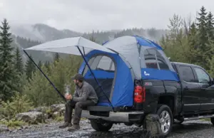 Truck Bed Tent Buying Guide Measure Your Bed First Man sitting on a pickup tailgate with a Napier Sportz truck bed tent pitched over the bed on a cool morning