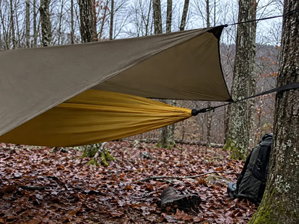 Coyote Brown hex hammock tarp extending past the gathered end of a hammock, checked from the side before settling in