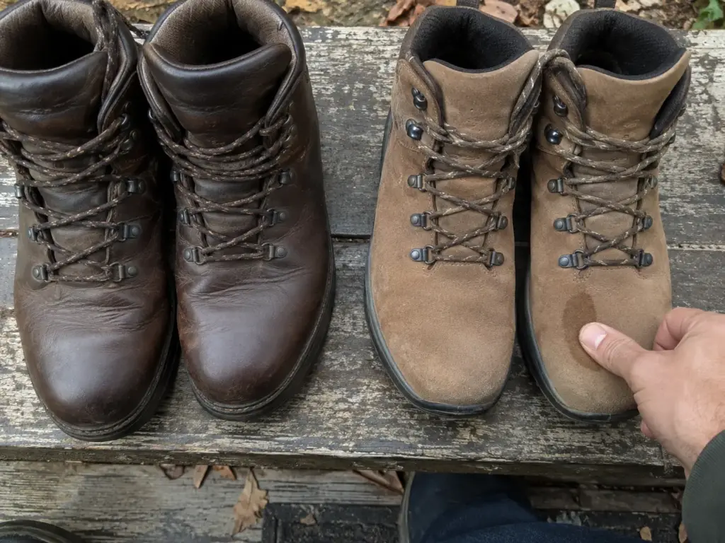 Two pairs of men's leather hiking boots on a porch step, smooth full-grain on the left and brushed nubuck on the right