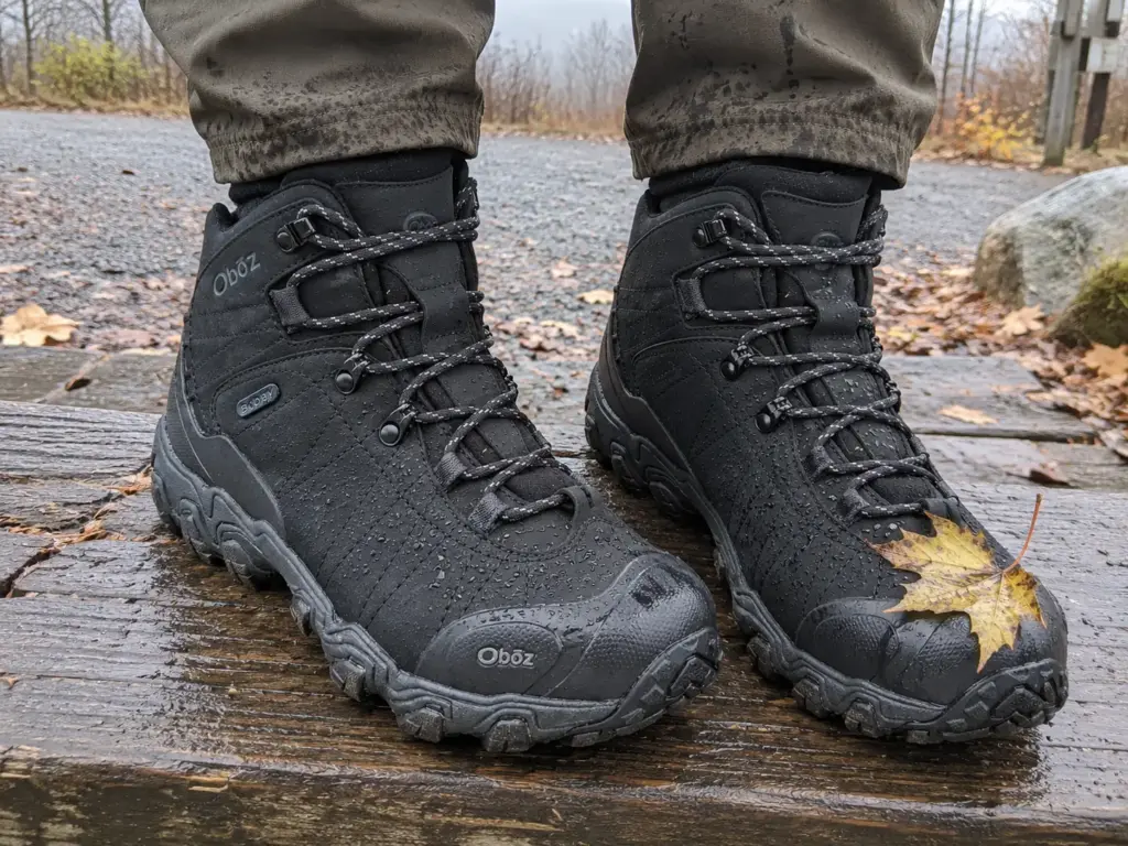A pair of Oboz Bridger Mid B-DRY leather hiking boots on a damp wooden trailhead step after a light rain