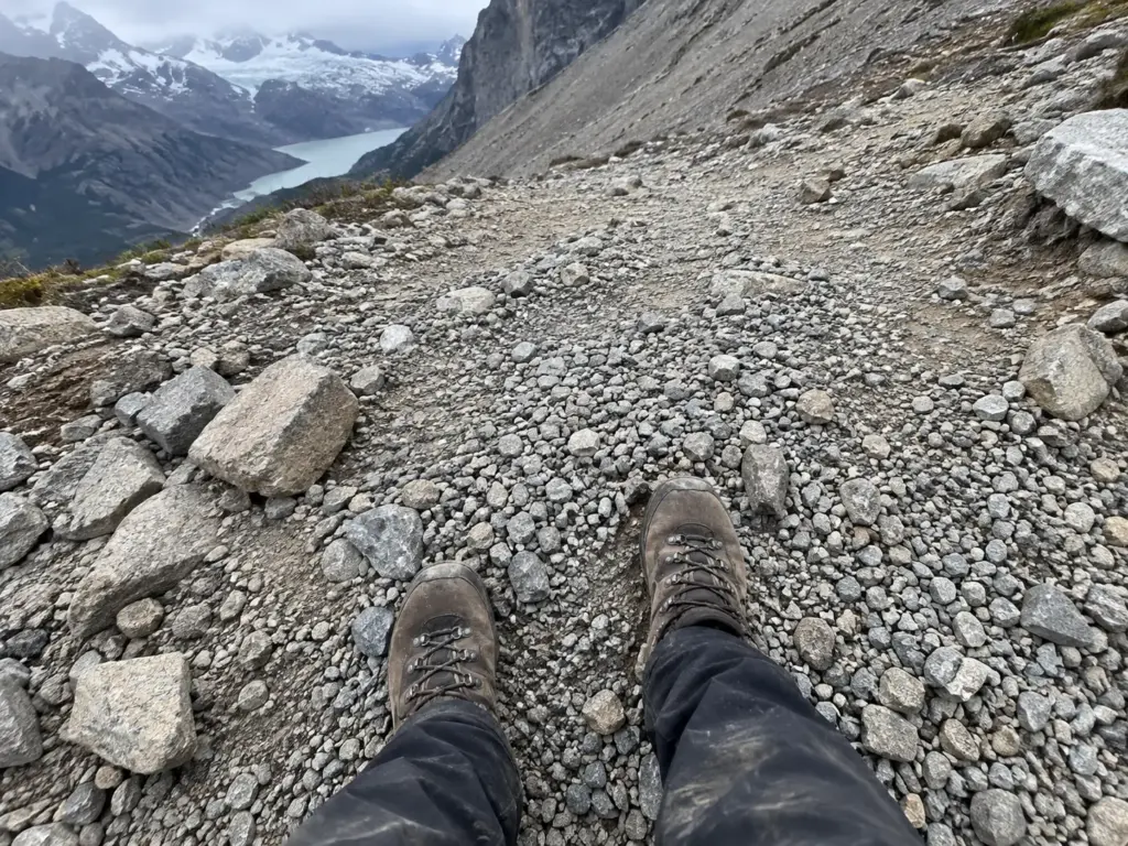 Worn hiking boots on the loose gravel of a steep path toward Laguna de los Tres, the climb behind a hard hiking rating