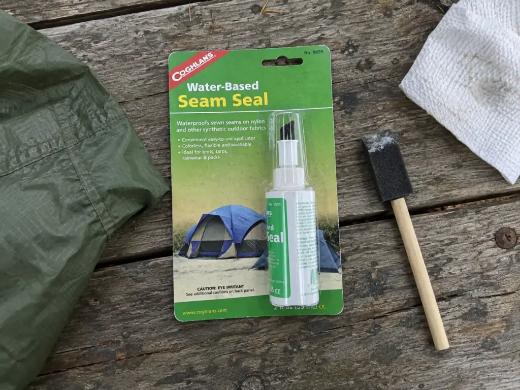 Coghlan's Tent Seam Sealer bottle, foam brush and a small jar on a porch table for a budget seam sealing job