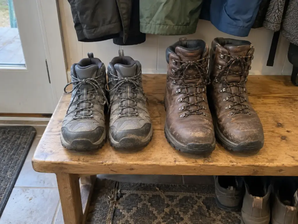 A lightweight fabric hiking boot beside a heavy leather hiking boot on a mudroom bench